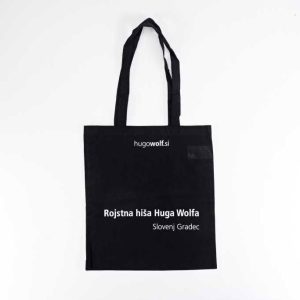 črna tekstilna vrečka z ročajema in belim napisom Rojstna hiša Huga Wolfa Slovenj Gradec